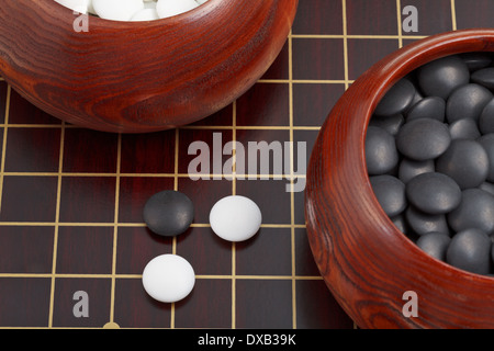 Bianco e nero gioco go pietre e ciotole di legno sul goban Foto Stock