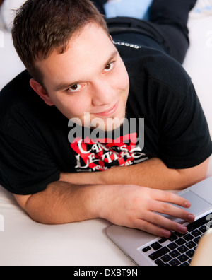 Giovane uomo nel letto con il computer portatile durante la navigazione in internet Foto Stock