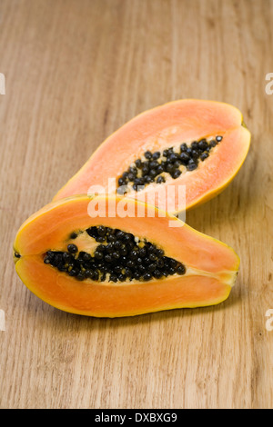 Carica papaya metà su una superficie di legno. Sezione trasversale del frutto di papaia. Foto Stock