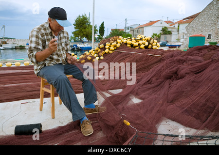 Fisherman riparazione rete da pesca in luogo Kali, isola di Ugljan, Dalmazia, Croazia Foto Stock