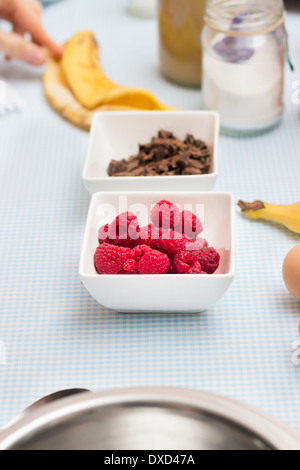 Il lampone e cioccolato closeup su un tavolo da cucina con altri ingredienti alimentari per rendere organico torta paleo Foto Stock