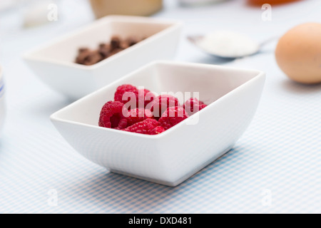 Lamponi closeup su un tavolo da cucina con altri ingredienti alimentari per rendere organico torta paleo Foto Stock