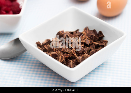 Primo piano di cioccolato su un tavolo da cucina con altri ingredienti alimentari per rendere organico torta paleo Foto Stock