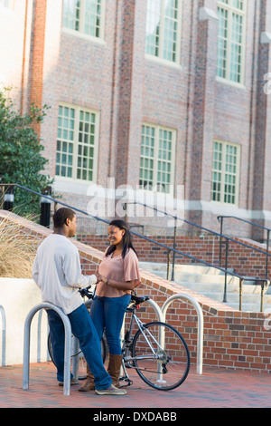 Coppia giovane all'aperto sul campus universitario, parlando accanto a portabiciclette, Florida, Stati Uniti d'America Foto Stock