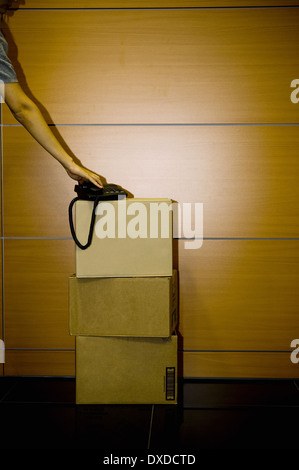 Mano sul telefono su scatole di cartone in office Foto Stock