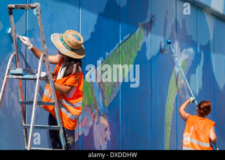 Gli studenti di arte pittura di un murale sulla parete del porto di Los Cristianos Tenerife Isole Canarie Spagna Foto Stock