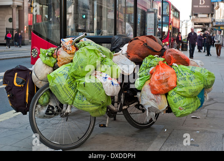 Le persone senza fissa dimora beni mondani in sacchetti di plastica appeso di una bicicletta a Londra Fermata Bus Foto Stock