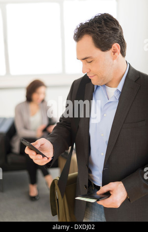 Imprenditore texting all aeroporto Foto Stock