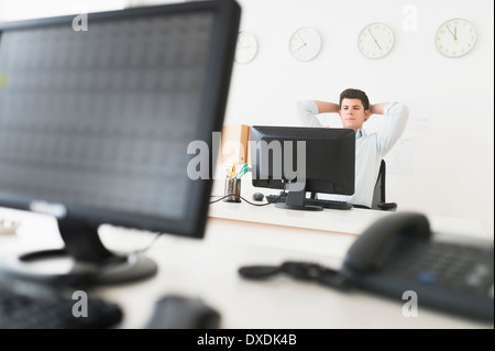 Giovane uomo seduto nella parte anteriore del banco di lavoro e Foto Stock