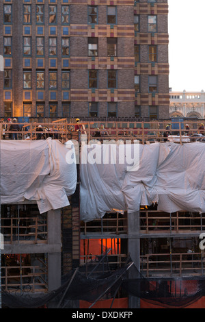 Alto edificio sito in costruzione con commercianti al crepuscolo, NYC, STATI UNITI D'AMERICA Foto Stock