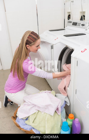 Donna caricamento della biancheria nella macchina di lavaggio Foto Stock