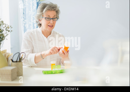 Donna matura la lettura di etichette sul flacone di farmaco Foto Stock