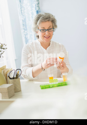 Donna matura la lettura di etichette sul flacone di farmaco Foto Stock