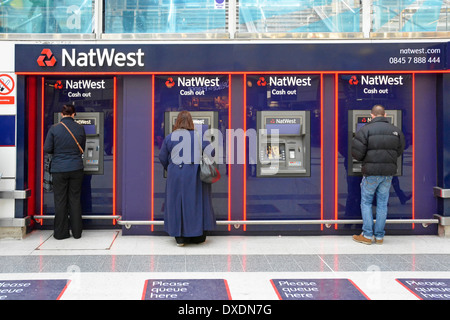 Nat West Bank moderna installazione di quattro ATM Bancomat sulla stazione ferroviaria concourse con coda qui segni Foto Stock