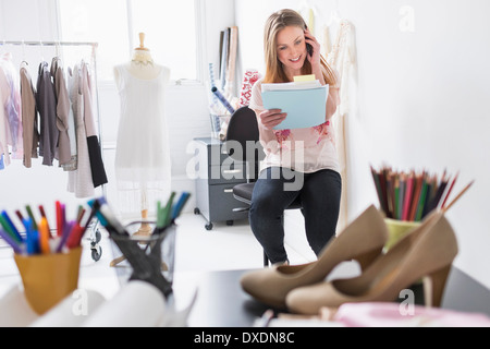 Ritratto di donna costumista tramite cellulare in studio Foto Stock
