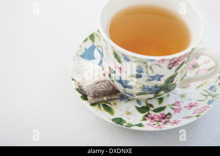 Tazza di tè in bella tazza floreale con piattino e utilizzato un sacchetto da tè, su sfondo bianco, studio shot Foto Stock
