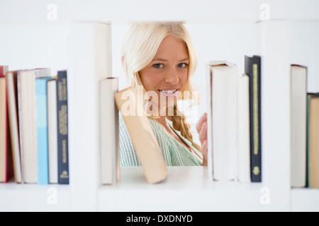 Ritratto di giovane donna spiata attraverso scaffale Foto Stock