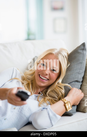 Giovane donna guardando la TV sul divano Foto Stock