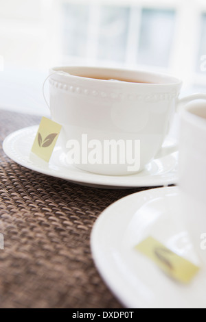 Due di colore bianco porcellana teacups con piattini e bustine di tè, studio shot Foto Stock