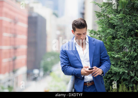 Giovane imprenditore rilassante quando la messaggistica di testo, la città di New York, nello Stato di New York, Stati Uniti d'America Foto Stock