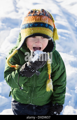 Ragazzo (4-5) controllare il gusto della neve Foto Stock