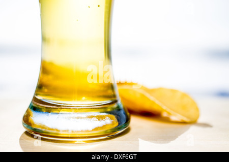 La pinta di birra. La formazione di schiuma di un bicchiere di birra e patatine in background. Foto Stock