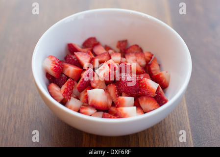 Fragole fresche a fette in una ciotola bianco su un tavolo di legno Foto Stock