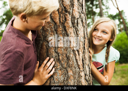 Un ragazzo e una ragazza a giocare all'aperto in piedi accanto ad albero nel parco, Germania Foto Stock