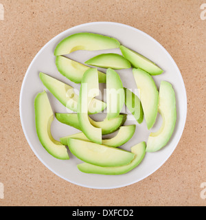 Fresco affettato avocado su piastra, su sfondo di legno. Foto Stock