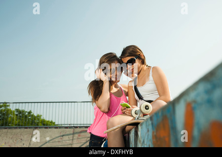 Ragazze guardando il lettore MP3 in Skatepark, Feudenheim, Mannheim, Baden-Württemberg, Germania Foto Stock