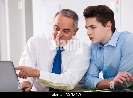 Imprenditore che mostra i dati del computer in apprendista in ufficio, Germania Foto Stock