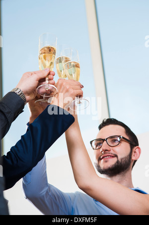 La gente di affari azienda bicchieri di champagne e tostando ogni altro in ufficio, Germania Foto Stock