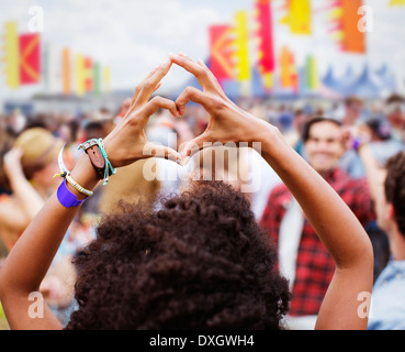 Donna cuore di formatura-forma con le mani al festival di musica Foto Stock