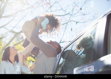 Padre figlia di sollevamento overhead fuori dall'auto Foto Stock