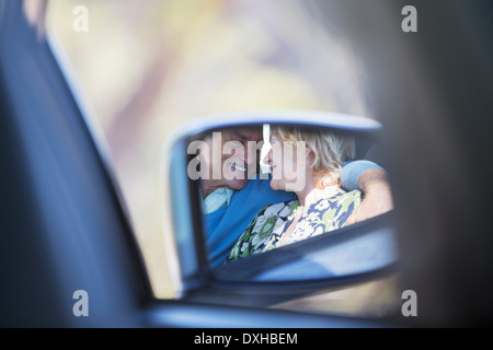 Vista laterale specchio di riflessione giovane costeggiata all'interno dell'auto Foto Stock