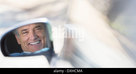 La riflessione di sorridere senior uomo in vista laterale specchio auto Foto Stock