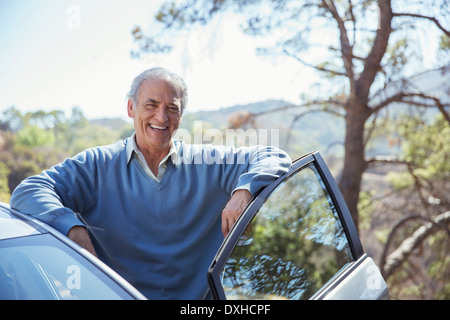 Ritratto di felice senior uomo appoggiato sulla macchina Foto Stock