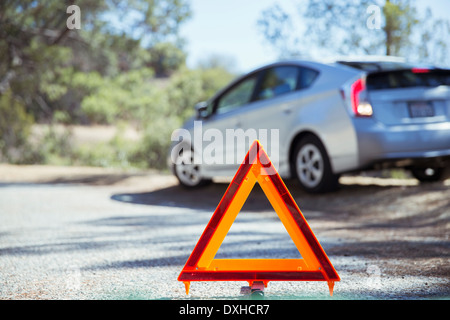 Auto in strada dietro il triangolo di avvertenza Foto Stock