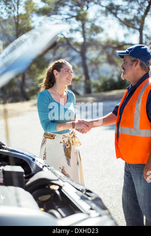 La donna si stringono la mano con il meccanico sul ciglio della strada Foto Stock