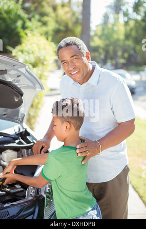 Ritratto del nonno sorridente a lavorare sulla vettura il motore con il nipote Foto Stock