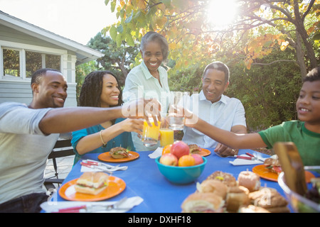 La famiglia felice di tostatura bicchieri di succo al patio tabella Foto Stock