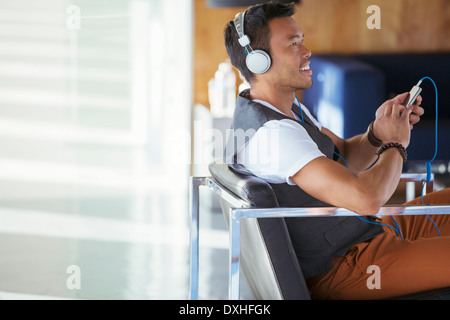 Imprenditore sorridente ascolto di musica sul lettore mp3 con cuffie Foto Stock