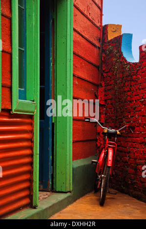 Una bicicletta rossa appoggiata contro una parete rossa a Buenos Aires, Argentina. Foto Stock