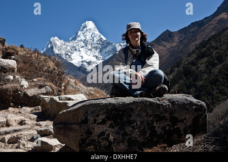 Donna seduta sul boulder con Amadablam mountain in background Valle Everest Nepal Foto Stock