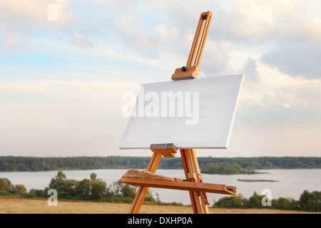 Una tela vuota si appoggia su un cavalletto sul paesaggio del lago Foto Stock