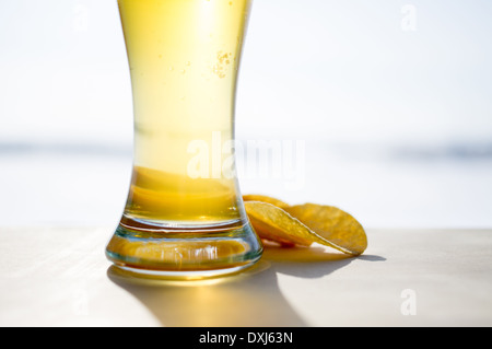 La formazione di schiuma di un bicchiere di birra e patatine in background. La pinta di birra Foto Stock