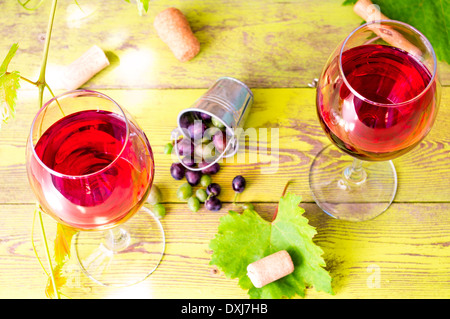 Due bicchieri di vino rosso accanto all'uva in una benna Foto Stock