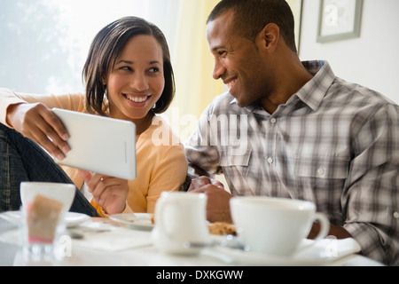 Coppia felice di bere il caffè e con tavoletta digitale Foto Stock