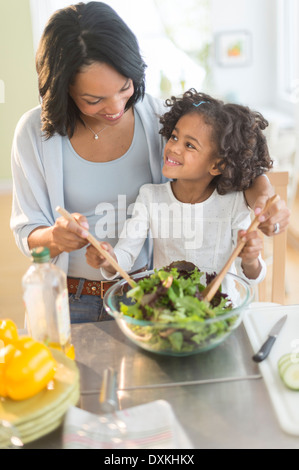 African American madre e figlia tossing salad Foto Stock