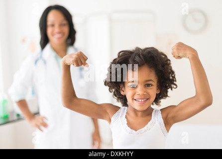 Ritratto di African American Girl muscoli di flessione nell'ufficio del medico Foto Stock